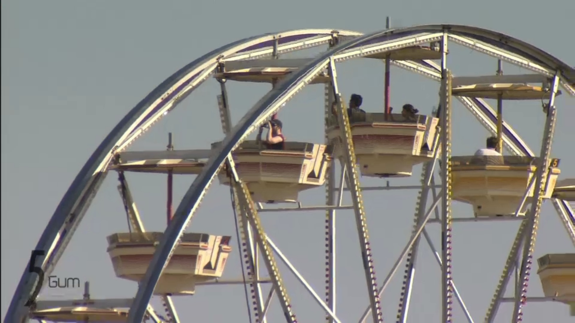 The Coachella Ferris wheel lit against a black night sky — red and gold tents glowing below, crowds silhouetted