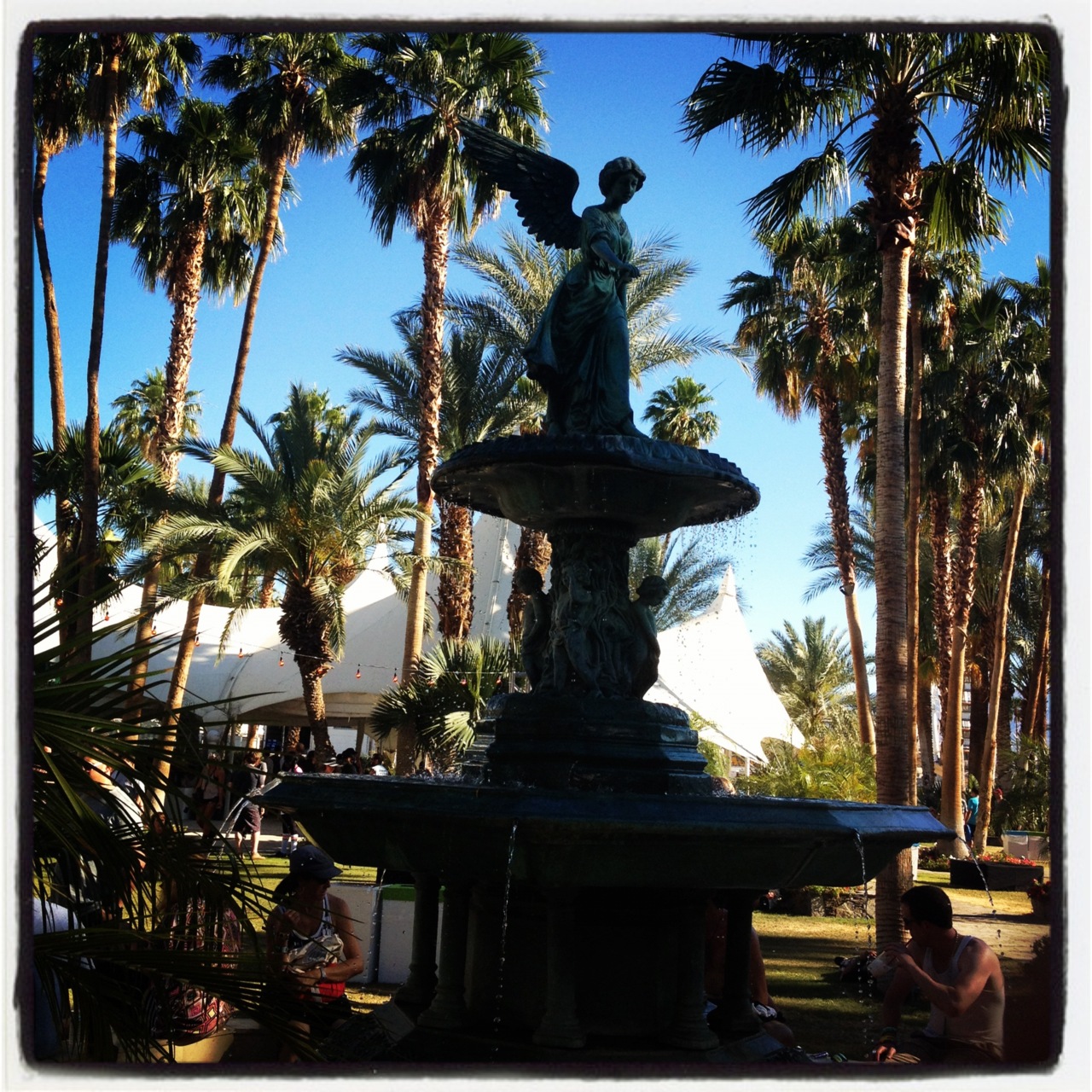 The Coachella main stage from the hill — desert mountains in the distance, palm trees, clear blue sky